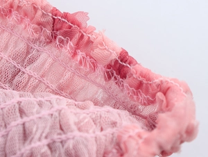 Primer plano macro de tela de malla rosa con detalles de volantes y encaje