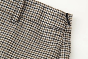 Detail of the side invisible zipper and waist belt loops on plaid textile fabric