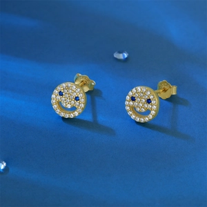 Detail of S925 sterling silver gold-plated smiley face stud earrings with blue zircon eyes