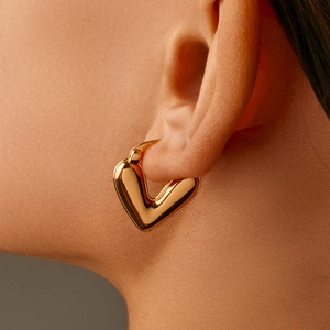 Macro shot of gold V-shaped huggie earrings with a polished mirror finish on the ear