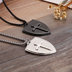 Detail of black and silver shield pendants with Bible verses on a wood surface