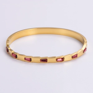 Detail view of pink ruby gemstones on a polished gold 304 stainless steel bangle