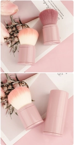 Detailed view of pink retractable makeup brush with dust cap and gradient soft bristles