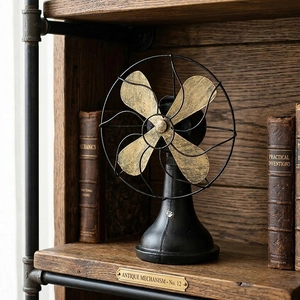Vintage industrial style black and gold electric fan ornament on a rustic wooden bookshelf