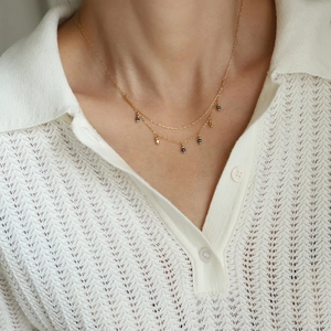 Detail of layered gold titanium necklace with blue beads shown on a model's neck