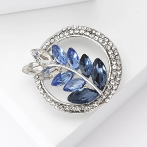 Macro shot of silver wreath brooch with sparkling blue and clear crystal leaf details