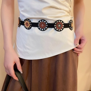 Detail of vintage bohemian waist chain with geometric floral metal discs on black leather