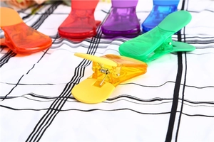 Dettaglio di clip di chiusura in plastica colorata trasparente su tessuto a quadri