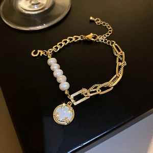 Macro shot of freshwater pearl bracelet with crystal smiley face and number 5 charm