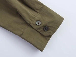 Detailed close-up of olive green twill shirt cuff featuring two pearl-finish buttons