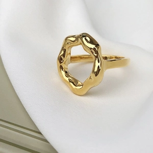 Gros plan d'une bague géométrique en acier doré 18 carats sur du satin blanc