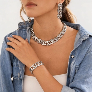 Silver metallic thick chain necklace bracelet and earring set worn on a denim shirt