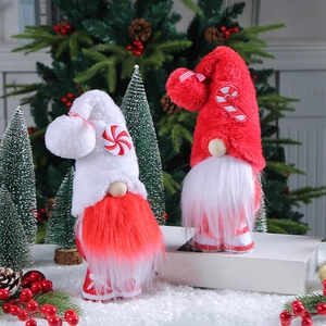 Set of two Christmas faceless gnome dolls with red and white candy canes in holiday scene