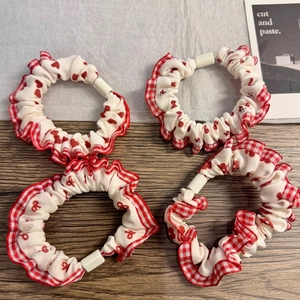 Set of four red plaid and heart print scrunchies with elegant ruffles on wooden background