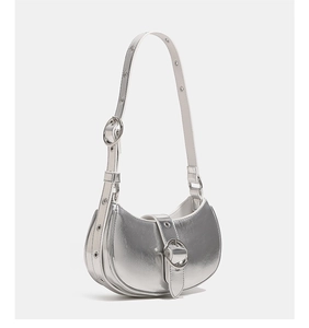 Close-up of metallic silver crescent bag featuring decorative rings and adjustable strap