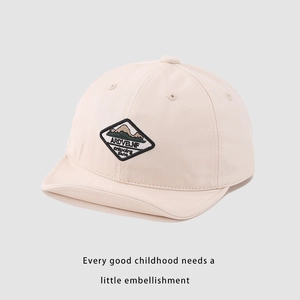 Close-up of cream cotton baby baseball cap with mountain patch and soft brim detail