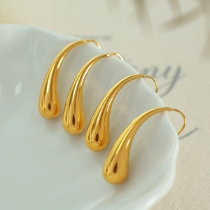 Elegant gold teardrop hook earrings displayed on a white ceramic tray for a chic look