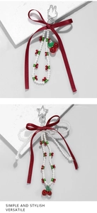 Detail of beaded bag charms with red ribbons, pearls and red cherry pendants on white base