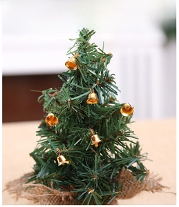 Close-up of a tabletop Christmas tree with gold bells and a rustic burlap wrapped base