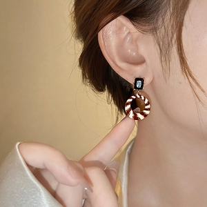 Macro shot of vintage round drop earrings with geometric enamel and sparkling zircons
