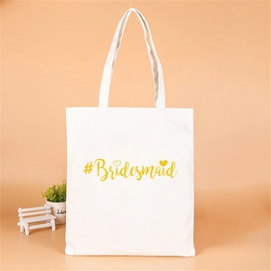 Close-up of white canvas bridesmaid tote bag with gold foil heart and lettering
