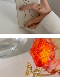 Detailed view of gold butterfly ring with hollow wings and sparkling zircon stone