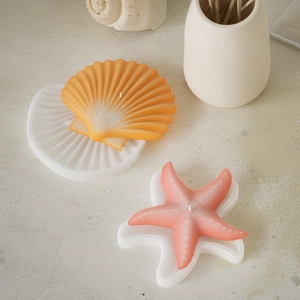 Starfish and seashell silicone molds with finished scented candles on a textured background