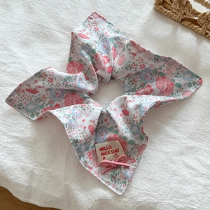 Detail view of pink and blue floral scrunchie with bow and Hello Nice Day fabric tag
