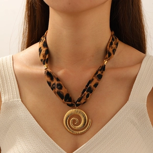 Close-up of leopard print ribbon necklace with a golden spiral pendant worn by model