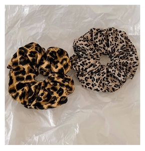 Detail of two leopard print scrunchies in dark and light fabric on white background