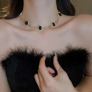 Detail of vintage gold necklace with black oval gemstones on a model neck