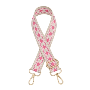 Close-up of woven ethnic bag strap in beige and pink with gold lobster clasps and slider