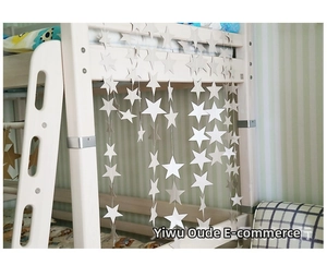 Close-up of white paper star garlands hanging on a wooden bunk bed for party decor