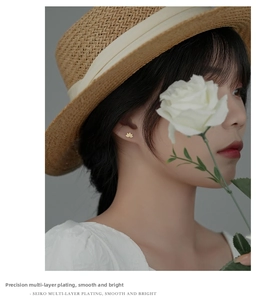 Close-up of golden lotus stud earring worn by a model in a romantic garden setting