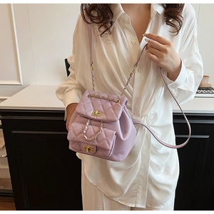 Detail of light purple quilted mini backpack with golden chain strap on a model