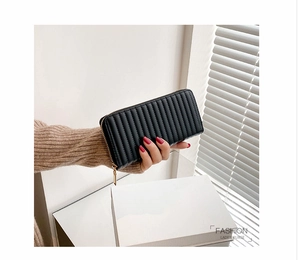 Detail of a black long PU leather wallet with vertical quilting and a golden zipper closure