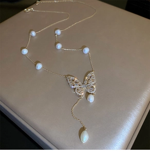 Detailed close-up of gold butterfly necklace with zircon stones and freshwater pearls