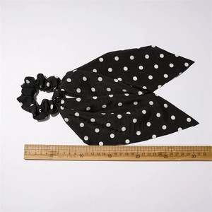Polka dot fabric scrunchie with long ribbons in black and white on white background