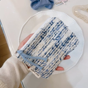 Dettaglio della mini borsa in tweed blu e bianco con cerniera e nappina decorativa
