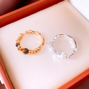Detail of 18K gold plated tiger eye bead ring and silver pearl ring in a jewelry box