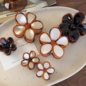 Detail of vintage amber flower hair claws in tortoiseshell and acrylic on a ceramic plate
