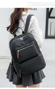 Rear view of a minimalist black school backpack worn by a model in a casual setting