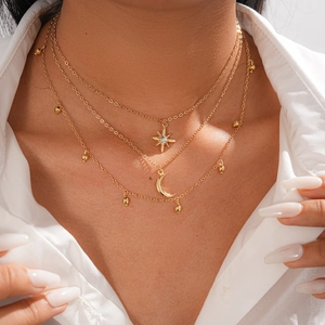 Close-up of triple-layered gold necklace with sparkling star and crescent moon charms