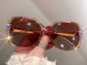 Détail de lunettes de soleil strass avec verres dégradés et papillons latéraux