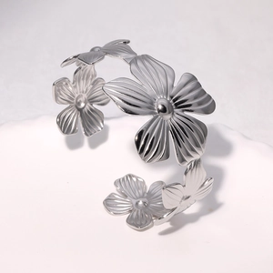 Detailed close-up of a silver stainless steel open bangle with five-petal flower motifs
