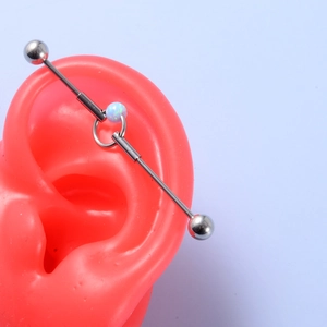 Industrial barbell earring detail with blue opal stone on silver stainless steel bar