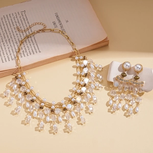 Vintage gold layered necklace and earring set with pearls and tassels on an open book