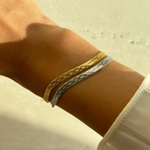 Close-up of gold and silver flat snake chain bracelets on wrist with natural lighting