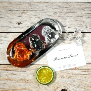 Close-up of penguin shaped ice cubes in orange and black on a stainless steel tray