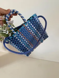 Detail of multi-color handwoven wicker bucket bag showing square checkered texture and handles